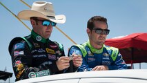 Austin Dillon, driver of the No. 3 Richard Childress Racing Chevy, and Casey Mears, driver of the No. 13 Germain Racing Chevy, ride atop a truck before the start of the FedEx 400 June 1, 2014, at Dover International Speedway in Dover, Del. Dillon is looking at a coin he received from Adm. James Winnefeld, Jr., Vice Chairman of the Joint Chiefs of Staff, earlier that day. (U.S. Air Force photo/Senior Airman Jared Duhon)