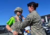 Staff Sgt. Joyce Bray, 436th Security Forces Squadron reports and analysis, fastens a buckle of a combat helmet on NASCAR fan, Nolan Bart June 1, 2014 at the Dover International Speedway in Dover, Del. The 436th SFS had battle-rattle equipment for fans to try on and brought out McGruff the Crime Dog to engage with the public during the NASCAR race weekend. (U.S. Air Force photo/Airman 1st Class William Johnson)