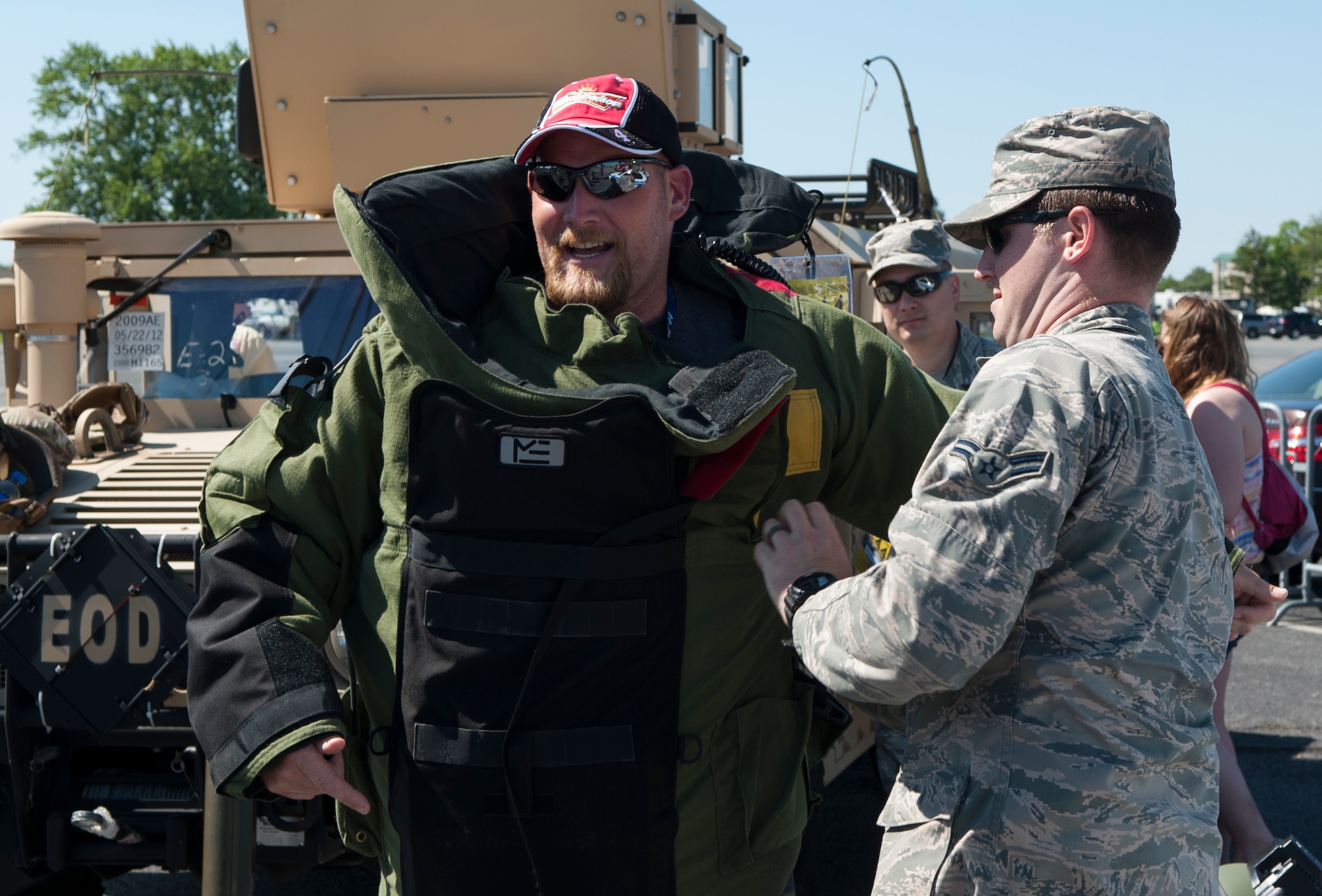 Airman 1st Class Coby Hillman 436th Civil Engineer Squadron explosive ordinance disposal apprentice, helps NASCAR fan, Kevin Townsend, put on an EOD bomb suit May 31, 2014, at the Dover International Speedway in Dover, Del. The EOD flight let NASCAR fans try on the bomb suit and get inside of a M1165 Humvee that was set up inside of the FunZone. (U.S. Air Force photo/Airman 1st Class Zachery Cacicia)