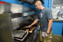 Staff Sgt. Brian Edwards, 9th Airlift Squadron flight engineer cooks hamburgers in a concession stand May 31, 2014 at the Dover International Speedway in Dover, Del. The 9th AS worked a concession stand selling food and drinks to raise money for their booster club during the NASCAR race weekend. (U.S. Air Force photo/Airman 1st Class William Johnson)