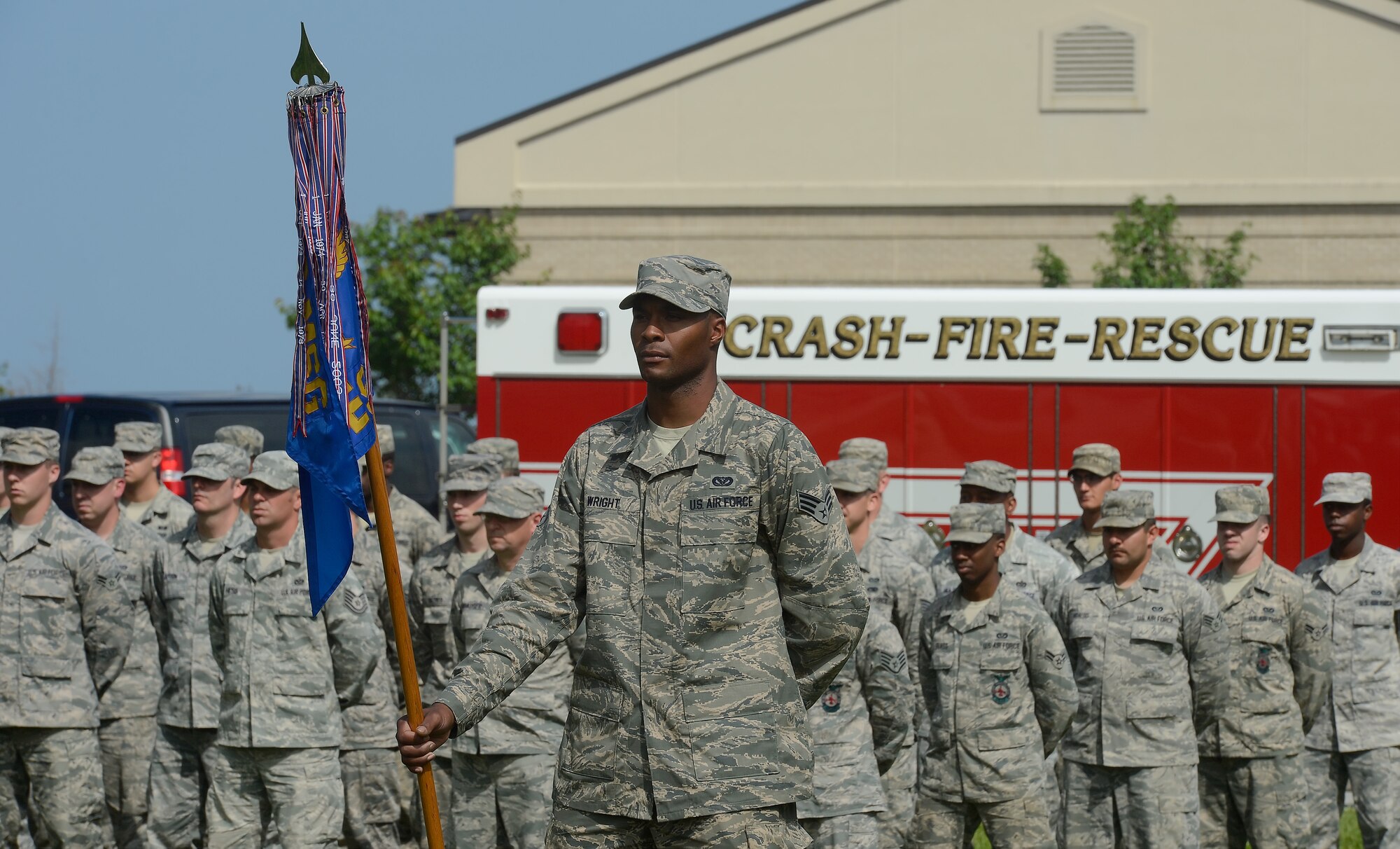 Senior Airman Andrew Wright, 436th Civil Engineer Squadron electrical shop, stands at parade rest while holding the unit guidon during a formal retreat ceremony performed by CES on May 30, 2014, at Dover Air Force Base, Del. A fire truck can be seen in the background and represents one section of the diverse squadron. (U.S. Air Force photo/Greg L. Davis) 