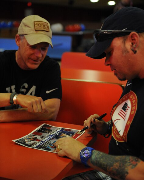 Patrick McDonald, a Paralympian curler, signs an autograph during the American 300 Skate-A-Thon at a skating rink in Bossier City, La., June 2, 2014. McDonald, a U.S. Army veteran, has competed in curling events around the world and is a part of the U.S. Paralympic curling team. (U.S. Air Force photo/Senior Airman Benjamin Gonsier) 