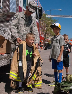 140531-F-CP692-025 Staff Sgt. Alex Klinger, 90th Civil Engineer Squadron Fire Department fire chief, places a fire jacket on Shawn Grady, 5, during an Armed Forces Day event in the Cheyenne Depot. The Warren Fire Department participated in the event by showcasing the tools they use in emergency situations. (U.S. Air Force photo by Capt. Eydie Sakura)