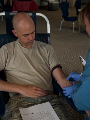 140530-F-GZ967-014 Jaime Garcia, United Blood Services donor care specialist, inserts a needle into the arm of 2nd Lt. Stefan Choquette, 90th Comptroller Squadron, May 30 during the monthly blood drive in the Fall Hall Community Center. (U.S. Air Force photo by Airman 1st Class Brandon Valle)