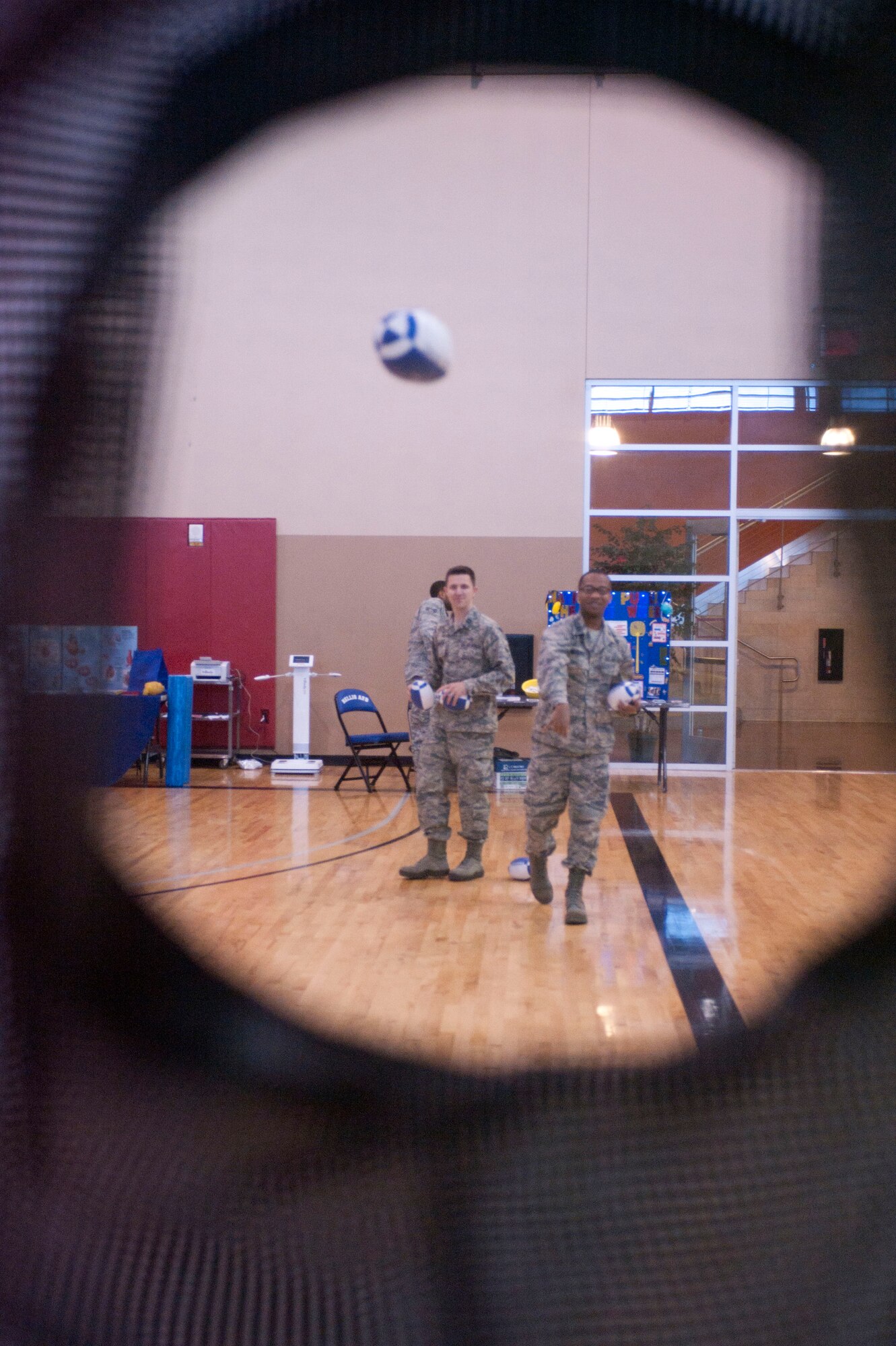 Capt. (Dr.) Wade Hinrichs (left) and Capt. (Dr.) Terrell Mitchell (right), 99th Dental Squadron dentists, take turns throwing indoor footballs at pockets on a standup simulating football receivers open for a catch during a Health Fair May 30, 2014 at Nellis Air Force Base, Nev.  One of the fitness center's goals during the health fair was to be a conduit for fitness information. (U.S. Air Force photo by Senior Airman Timothy Young)