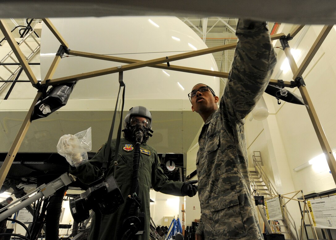 Senior Airman Christopher Robnett, 28th Operations Support Squadron aircrew flight equipment technician, instructs Col. Kevin Kennedy, 28th Bomb Wing commander, on the proper procedure for decontaminating the mask and helmet during an aircrew chemical defense ensemble training at Ellsworth Air Force Base, S.D., May 29, 2014. The mask wipe and helmet decontamination station helps prevent the spread of contaminants. (U.S. Air Force photo by Senior Airman Anania Tekurio/Released)
