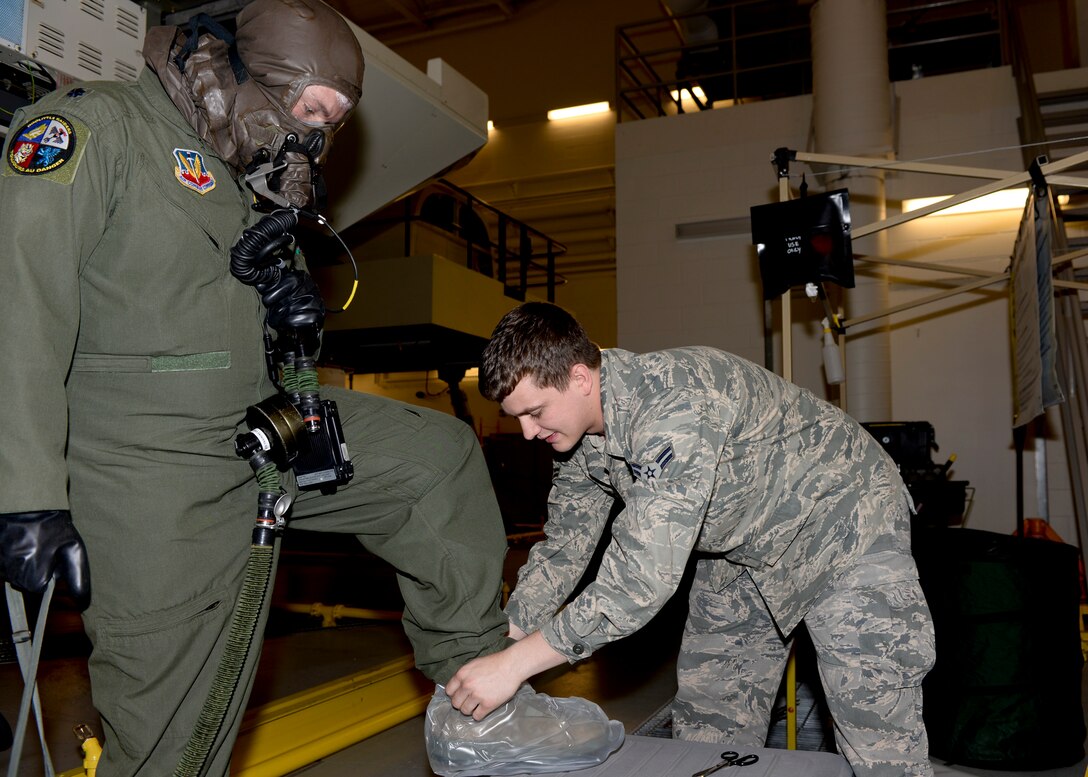 Airman 1st Class James Ash, 28th Operations Support Squadron aircrew flight equipment technician, removes protective covers off of Lt. Col. Jason Yeatts, 28th Operations Group deputy commander, during aircrew chemical defense ensemble training at Ellsworth Air Force Base, S.D., May 29, 2014. The suit consists of a protective respiratory mask, undergarments and gloves. (U.S. Air Force photo by Senior Airman Anania Tekurio/Released)