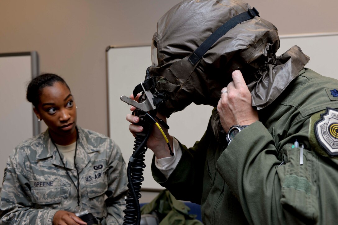 Staff Sgt. Candace Greene, 28th Operations Support Squadron aircrew flight equipment technician, assists Lt. Col. Jason Yeatts, 28th Operations Group deputy commander, with donning gear during aircrew chemical defense ensemble training at Ellsworth Air Force Base, S.D., May 29, 2014. The training prepares aircrew to survive and operate in a chemically contaminated environment. (U.S. Air Force photo by Senior Airman Anania Tekurio/Released)