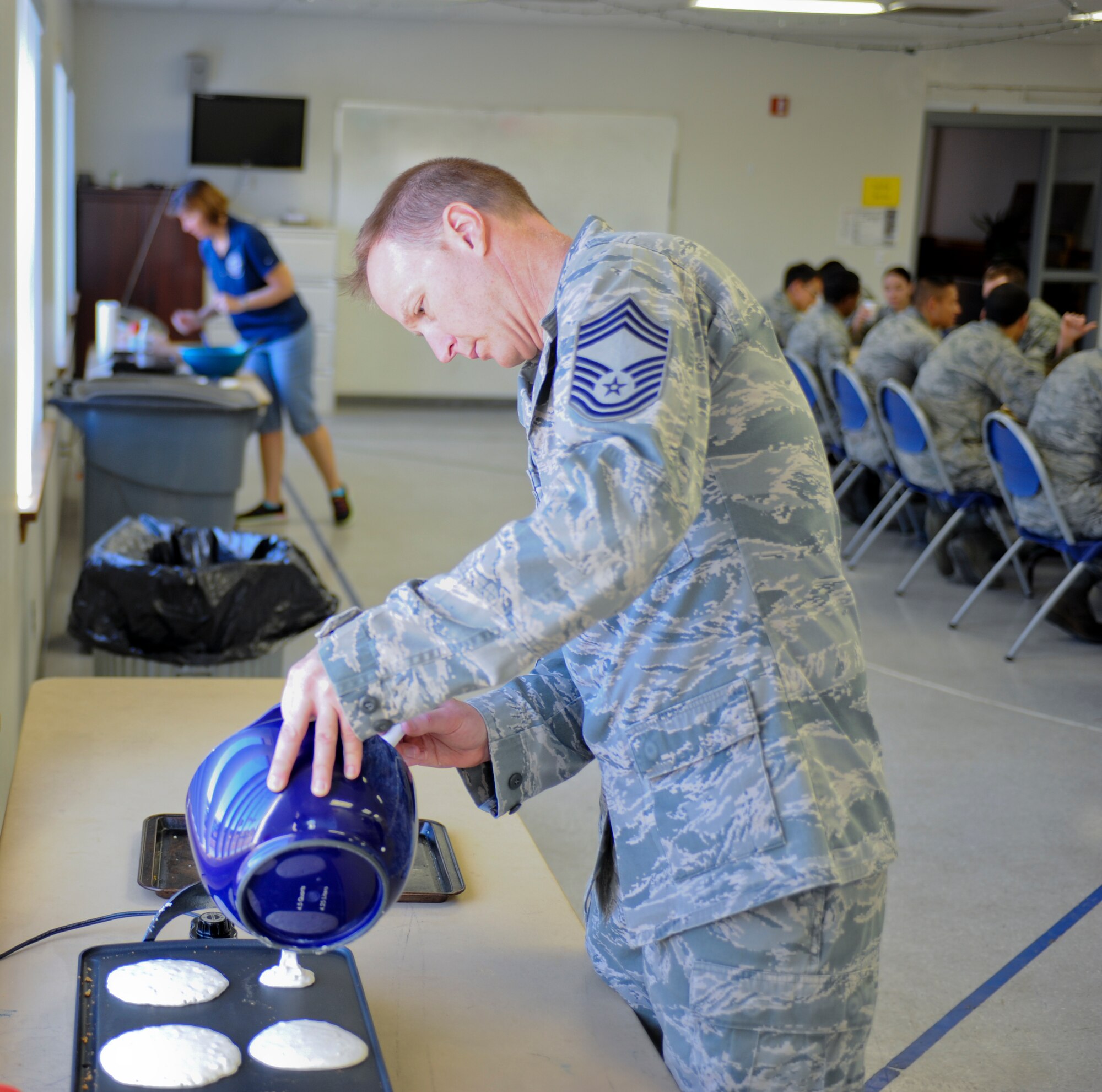 U.S. Air Force Chief Master Sgt. Kelly Downey, 355th Maintenance Group chief, pours pancake batter on a hot plate at a pancake social during a Comprehensive Airman Fitness Day at Davis-Monthan Air Force Base, Ariz., June 2, 2014. CAF is an Air Force-wide initiative based on improving Airmen readiness by solidifying the four pillars of CAF: mental, physical, social and spiritual. (U.S. Air Force photo by Senior Airman Sivan Veazie/Released)