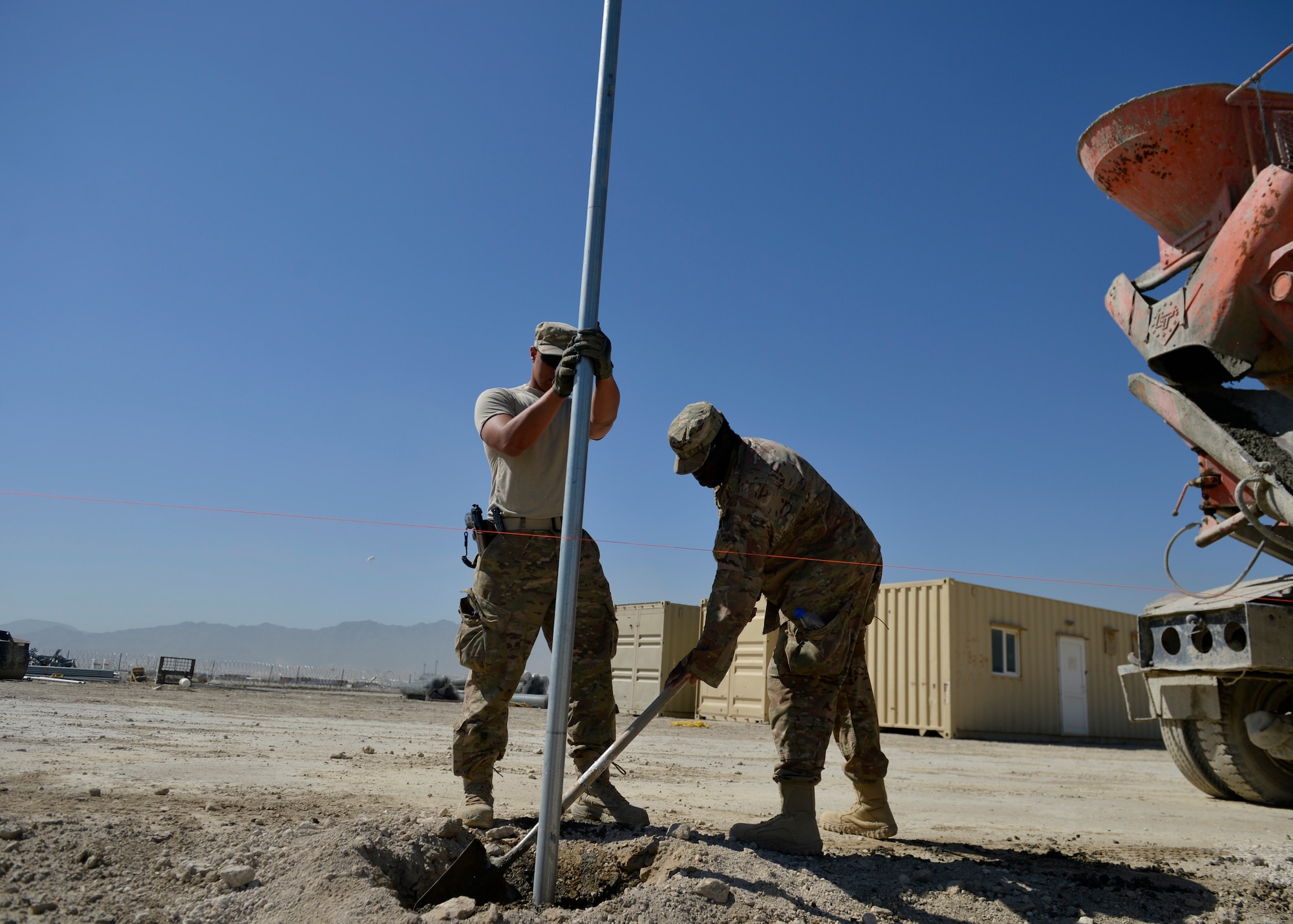 (From left) U.S. Air Force Airman 1st Class Patrick Henry Alexander and Staff Sgt. William Thomas, 577th Expeditionary Prime Base Engineer Emergency Force Squadron troop constructions, flatten freshly poured cement at Bagram Airfield, Afghanistan May 24, 2014.  Members from the squadron, poured cement to secure poles for a new security fence around the airfield.  The 577th EPBS brings together civil engineering Airmen from across several specialties to perform forward deployed construction work. Henry Alexander is deployed from Davis Monthan, Ariz. and a native of Gainesville, Fla.  Thomas is deployed from Ramstein Air Base, Germany and a native of Cincinnati, Ohio.  (U.S. Air Force photo by Staff Sgt. Evelyn Chavez)