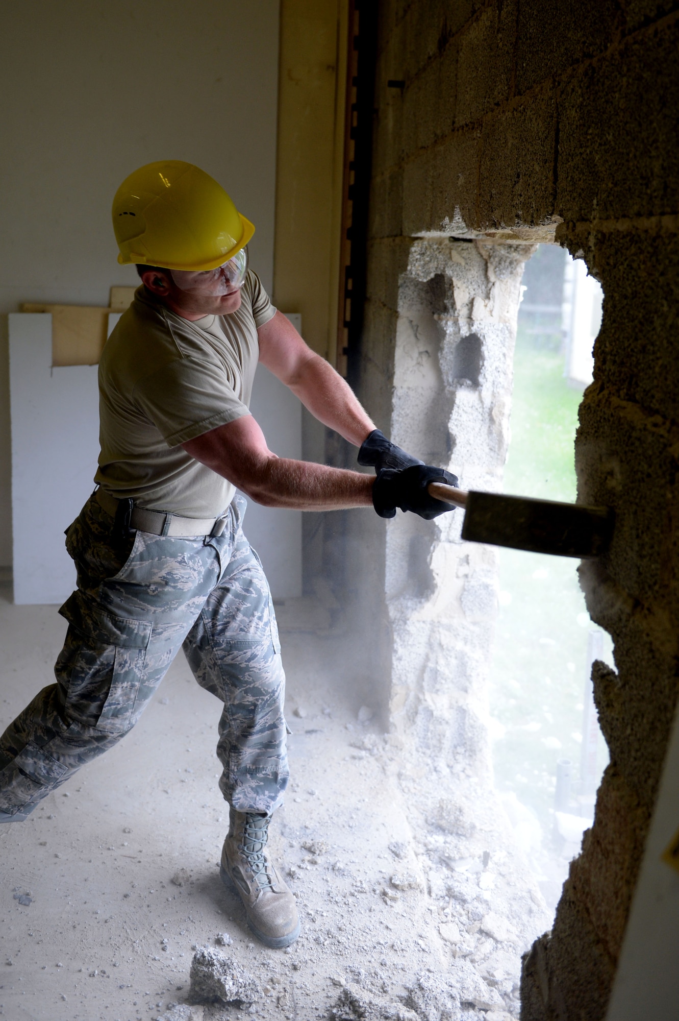 U.S. Air Force Senior Airman Richard Adamson, 52nd Civil Engineer Squadron structures journeyman from Linton, Ind., uses a sledge hammer to create an opening for a doorway in the Skelton Memorial Fitness Center racquet ball courts at Spangdahlem Air Base, Germany, June 3, 2014. The project is part of the remodel of the new combat fitness center which is scheduled to be finished between four and six months. (U.S. Air Force photo by Senior Airman Alexis Siekert/Released)