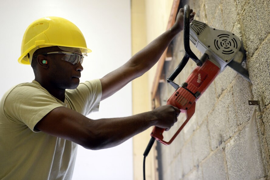 U.S. Air Force Airman 1st Class Marcelus Grant, 52nd Civil Engineer Squadron structures journeyman from Sandhill, Miss., uses a scissor saw to cut masonry block in the Skelton Memorial Fitness Center racquet ball courts at Spangdahlem Air Base, Germany, June 3, 2014. Structures Airmen are converting the courts into a new combat fitness area. (U.S. Air Force photo by Senior Airman Alexis Siekert/Released)