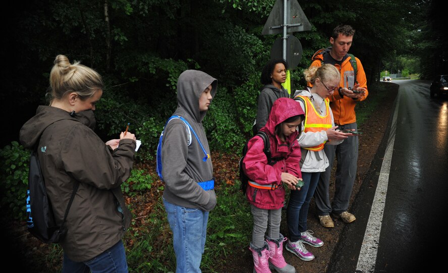 Advancement via Individual Determination students navigate to their coordinates with the assistance of one of their teachers and a survive, evade, resist and escape specialist guiding them along the way during the navigational challenge in Landstuhl, Germany, May 23, 2014. AVID is an elective class, geared toward assisting students in learning how to take notes, study and prepares them for college. AVID students from Ramstein Middle School were given the tools and knowledge needed to learn land navigation by 86th Operational Support Squadron’s survive, evade, resist and escape specialists. After five months of classroom sessions, AVID students were able to put their skills to the test by participating in the first ever NAVid Challenge, where they had to find their way from one point to another. (U.S. Air Force photo/Senior Airman Hailey Haux)