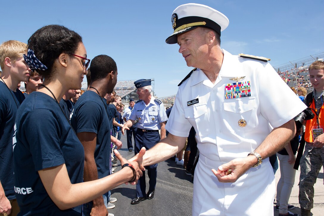 Navy Adm. James A. Winnefeld Jr., vice chairman of the Joint Chiefs of Staff, coins a new U.S. military enlistee after she was just sworn in, before the start of the FedEx 400 NASCAR race at the Dover International Speedway, in Dover, Del., June 1, 2014. 