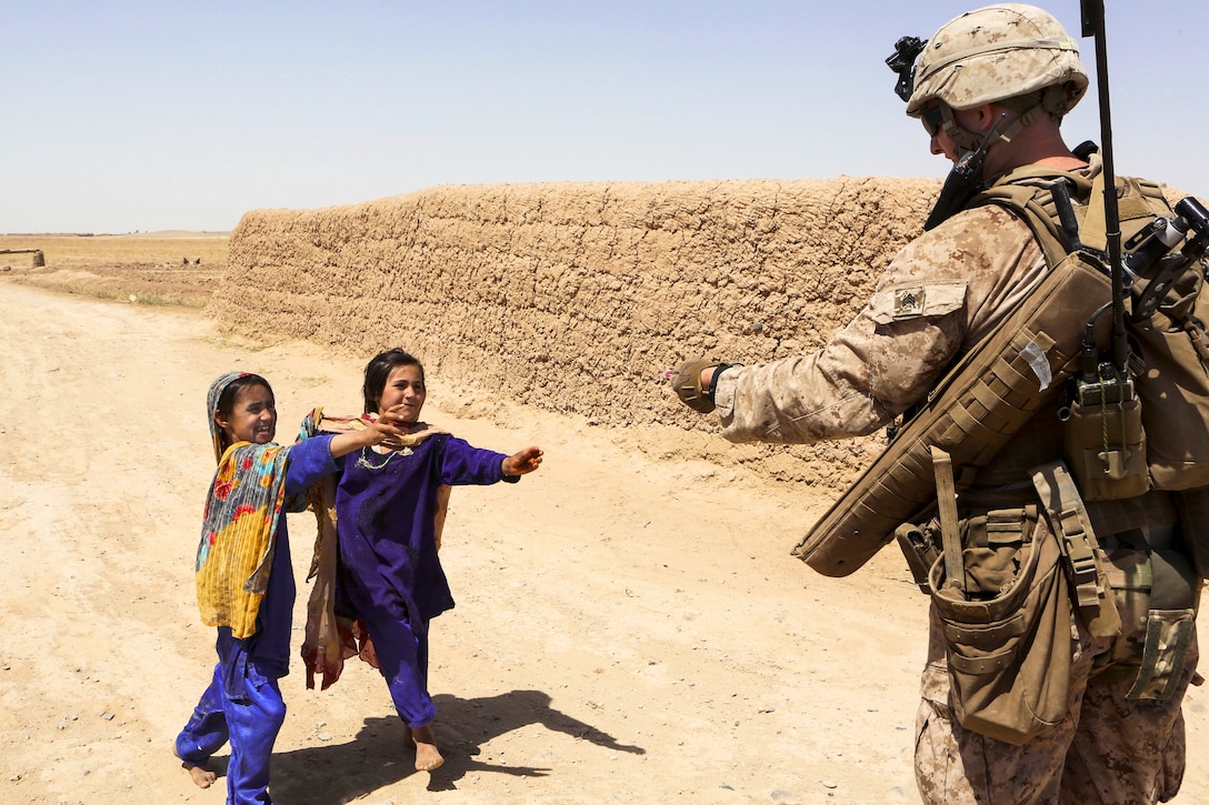 U.S. Marine Corps Sgt. Steven Hanson hands candy to local Afghan children during a security patrol near the town of Boldak in Helmand province, Afghanistan, May 21, 2014. Hanson, a squad leader, is assigned to 1st Battalion, 2nd Marine Regiment.