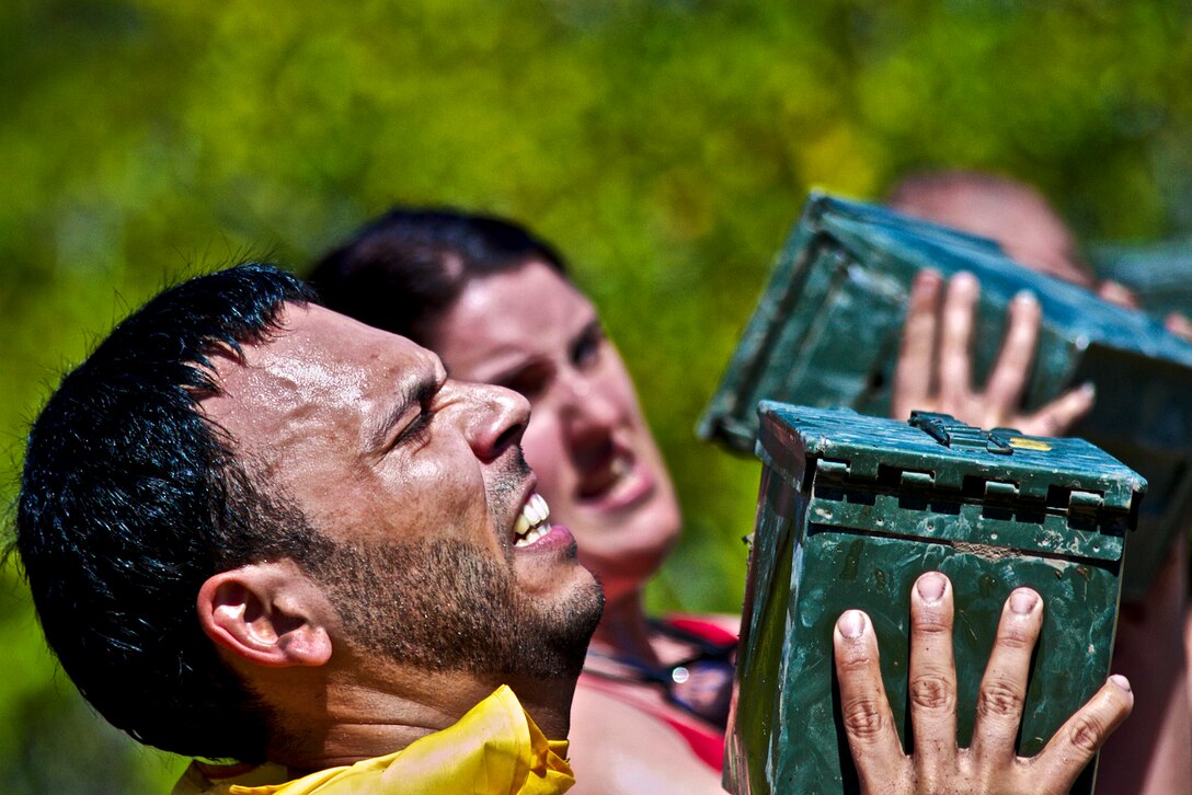 A participant in the Miami Superhero Scramble struggles to press an ammo can over his head during the Marine Mile section of the obstacle course in Fort Lauderdale, Fla., March 24, 2012. The Superhero Scramble is 3.5 miles of rugged terrain with more than 18 obstacles, including major water crossings. The race tests the competitors’ resilience, strength and endurance. 
