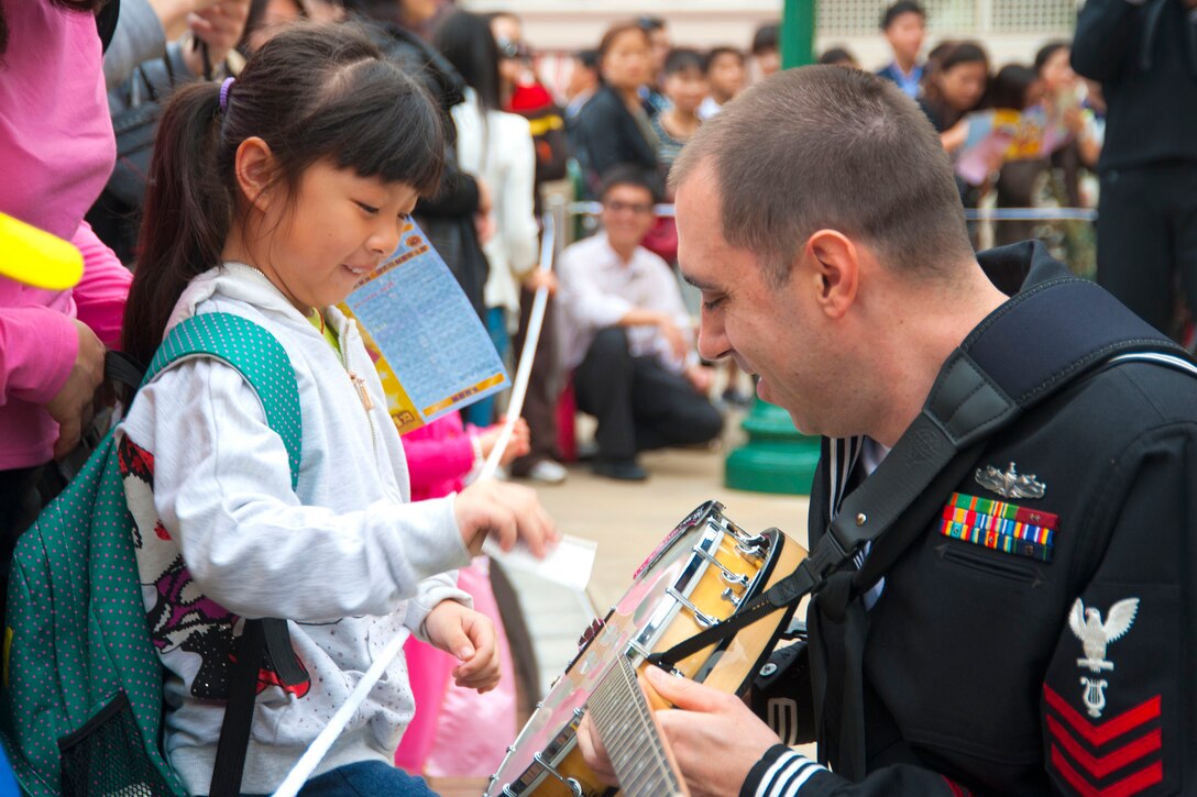 U.S. Navy Petty Officer 1st Class Brian Nefferdorf teaches a girl how to strum the banjo while his band performs in front of about 800 people at Hong Kong Disneyland in Hong Kong, March 19, 2012. Sailors from the U.S. 7th Fleet flagship USS Blue Ridge are in Hong Kong for a port visit. Nefferdorf plays with the Pacific Ambassaors, the U.S. 7th Fleet's band.  

