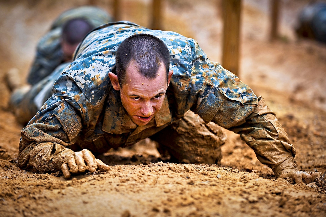 Soldiers low crawl while negotiating an obstacle course during their first week of basic combat training on Fort Benning, Ga., March 9, 2012.  
