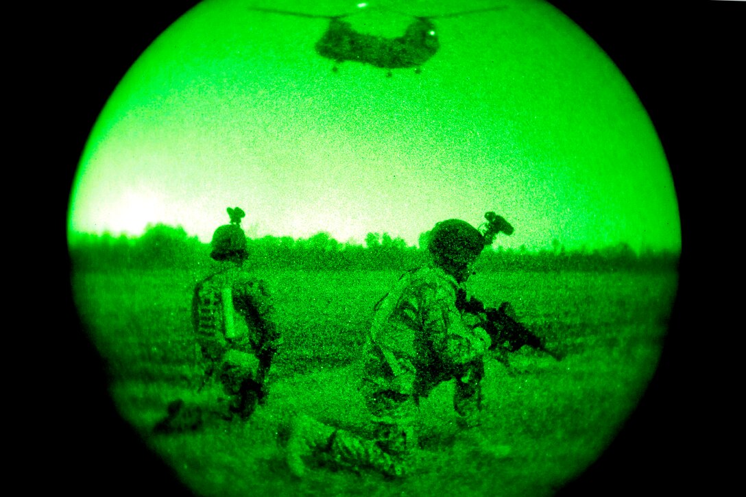 As seen through a night-vision device, soldiers conduct a night raid mission and provide security as a CH-47 Chinook helicopter circles overhead during exercise Emerald Warrior near Hattiesburg, Miss., March 5, 2012.  
