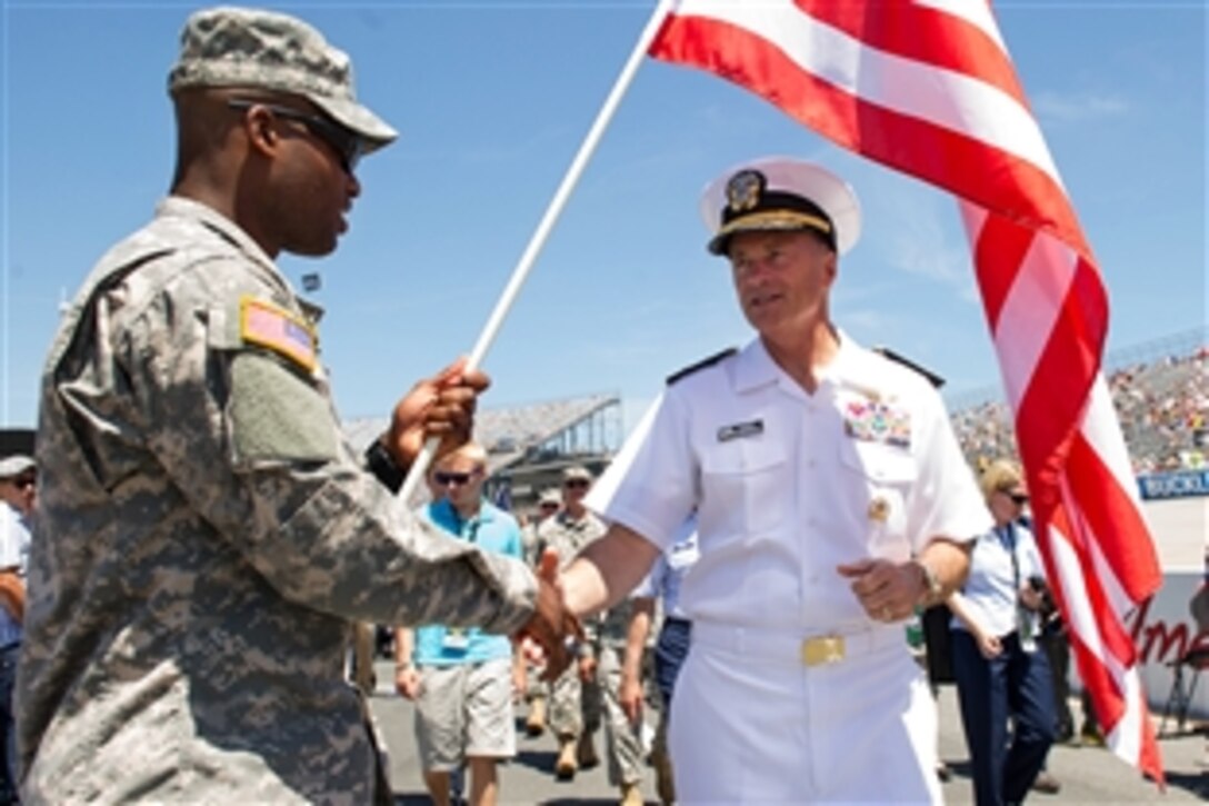 Navy Adm. James A. Winnefeld Jr., vice chairman of the Joint Chiefs of Staff, coins a soldier for his service and participation before the start of the FedEx 400 NASCAR race at the Dover International Speedway in Dover, Del., June 1, 2014.