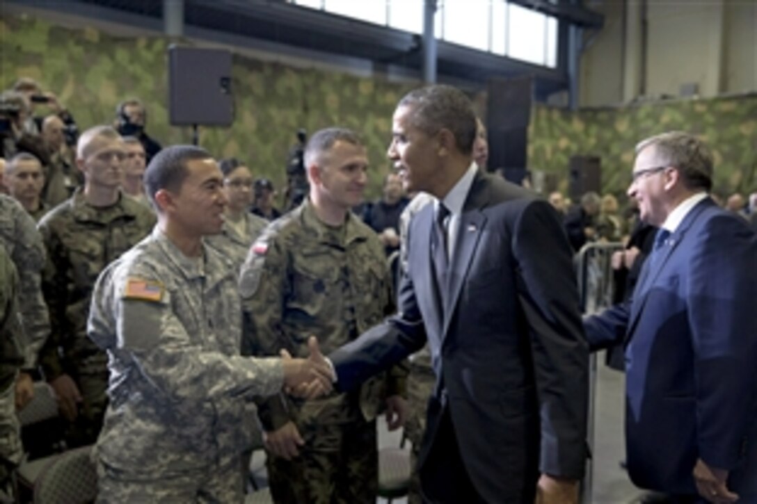 U.S. President Barack Obama and Polish President Bronislaw Komorowski of Poland greet audience members during a U.S. aviation detachment F-16 event at Warsaw Chopin Airport in Warsaw, Poland, June 3, 2014.