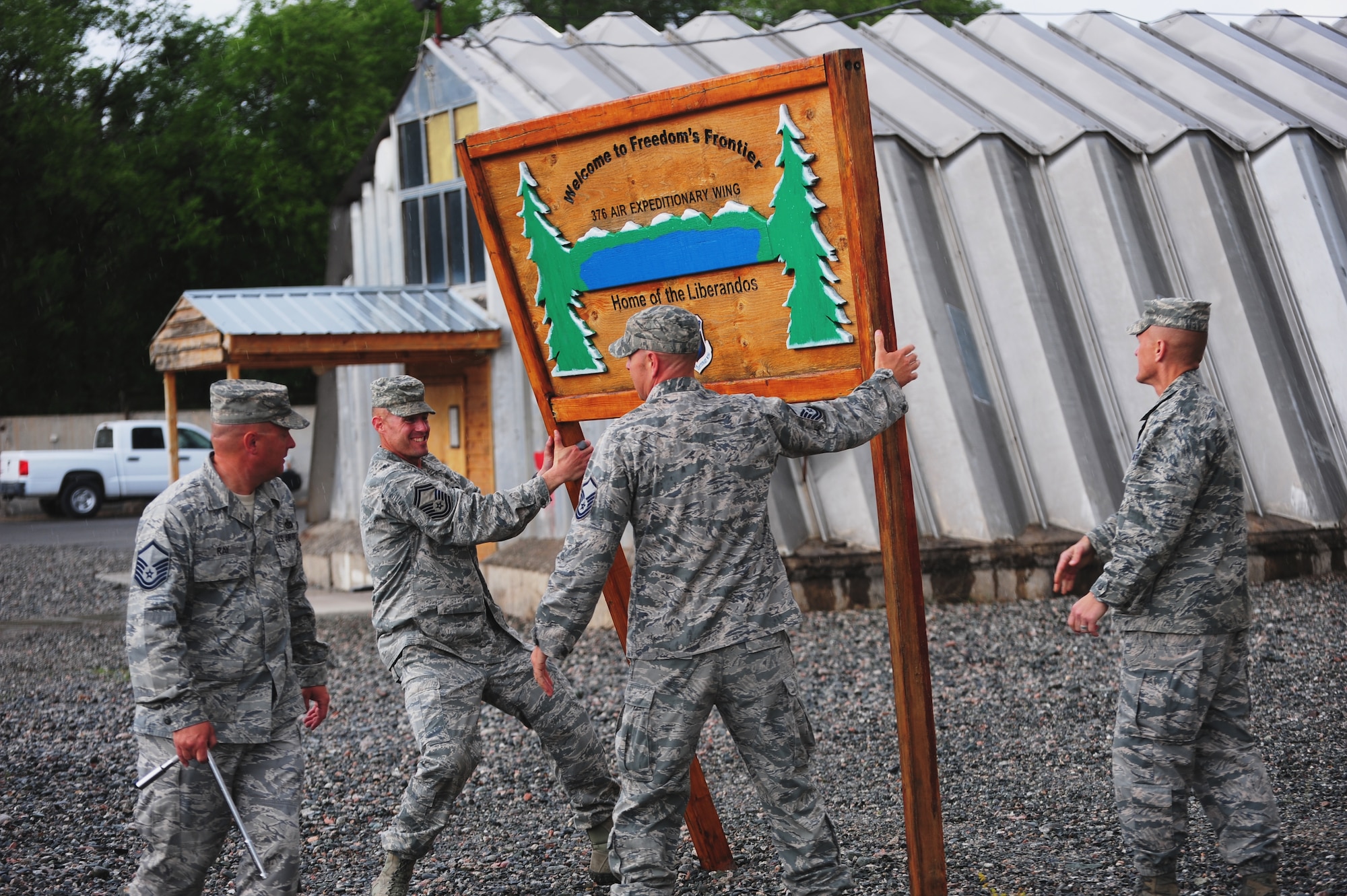 Airmen bring down the iconic sign outside the 376th Air Expeditionary Wing headquarters after the wing's inactivation ceremony June 3, 2014, at Transit Center at Manas, Kyrgyzstan. During its more than 12-year tenure, the wing performed four critical missions including air refueling, onward movement, airlift and humanitarian assistance. (Courtesy photo)