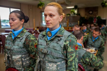Albanian Officer Candidates Ermiona Laci, left, and Anita Gruda stand in front of their table at the dining facility at Joint Base McGuire-Dix-Lakehurst, N.J., May 29, 2014. The candidates will remain standing until two additional candidates join them. Albania is the first State Partnership Program country to send its officer candidates to the United States to attend an Officer Candidate School program. The 12-week NJARNG OCS program is modelled after the active-duty program at Fort Benning, Ga., and includes classroom instruction, physical and leadership training. 