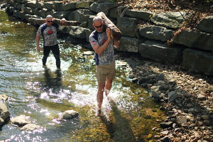 Sgt. 1st Class Sterling Deck and Army Maj. Cary Gilman, both from the National Guard Bureau Office of the Inspector General, navigate a shallow stream while carrying heavy logs on their shoulders Apr. 6, 2012 in Arlington Va. Deck and Gilman were training for the Spartan Death Race, a 48 hour endurance race scheduled for June 15 in Pittsfield, Vt. Their training session also included sprinting up and down hill while carrying heavy packs and tires, simulating wood chopping with a sledgehammer and tire and performing other exercises in timed circuits.