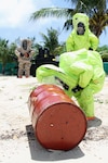 Members of the Guam National Guard's 94th Civil Support Team (Weapons of Mass Destruction) examine barrels that were simulated to have washed ashore and said to contain unknown chemicals during Kontra I Piligru, a two-day multi-agency maritime exercise held recently on the island of Guam.