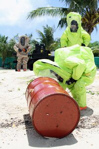 Members of the Guam National Guard's 94th Civil Support Team (Weapons of Mass Destruction) examine barrels that were simulated to have washed ashore and said to contain unknown chemicals during Kontra I Piligru, a two-day multi-agency maritime exercise held recently on the island of Guam.