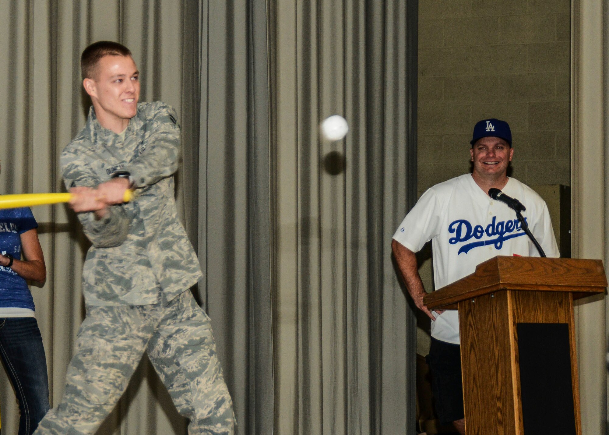 Airman 1st Class Austin Duncan, 412th Medical Operations Squadron, takes a swing at a whiffle ball as Master Sgt. William Russell, looks on in L.A. Dodgers gear. The theme of this  quarter's award ceremony was baseball where everyone was invited to support their favorite Major League team. Duncan was award the Dorm of the Quarter award. All winners were given the chance for a one-pitch at-bat to hit the ball into the cheering audience.  (U.S. Air Force photo by Rebecca Amber)