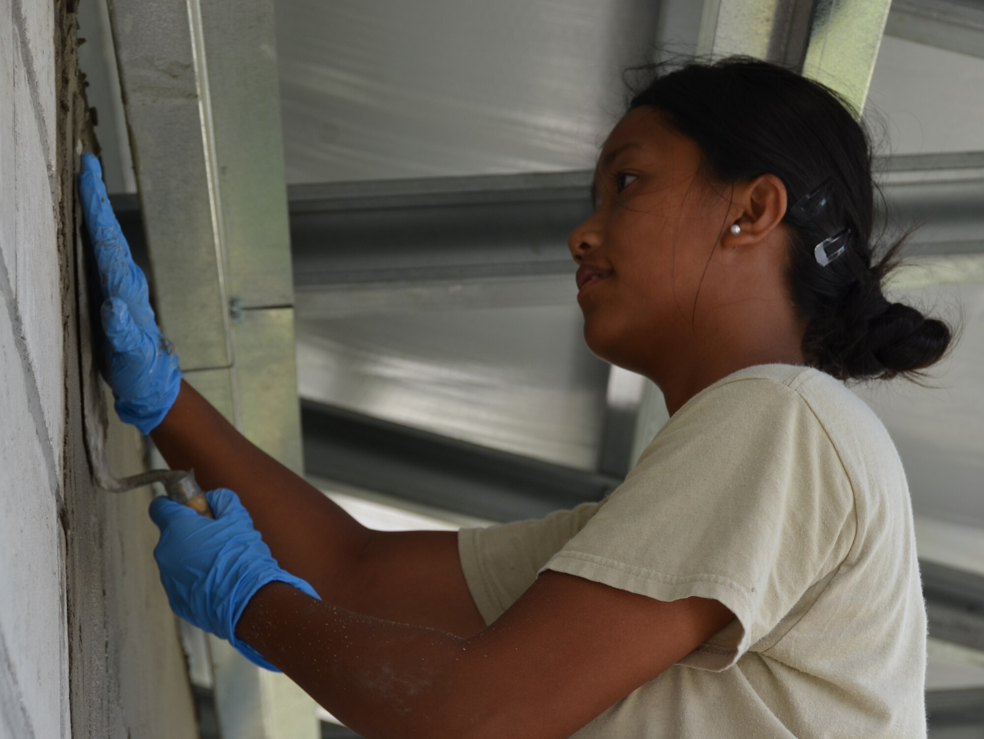 Senior Airman Janna Harina, an emergency medical technician deployed from the 4th Medical Operations Squadron, Seymour-Johnson Air Force Base, N.C., parges an exterior wall at the Sadie Vernon Technical High School in Belize City, Belize, May 15, 2014. Harina is deployed in support of the U.S. Southern Command-sponsored New Horizons exercise.