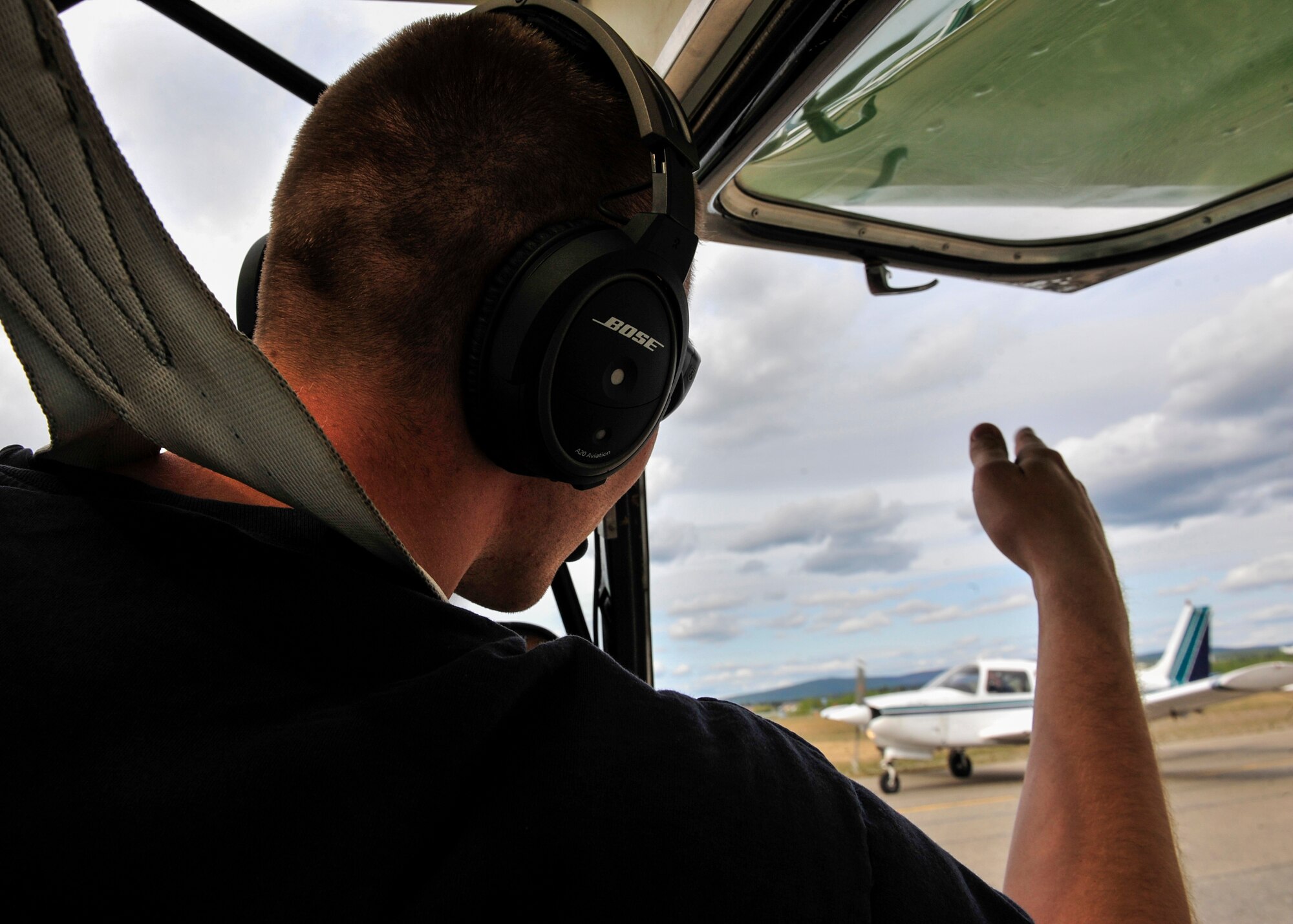 Senior Airman Alex Mumley-Dupuis, 354th Operations Support Squadron airfield management shift lead, waves to another pilot during Fairbanks Aviation Day May 17, 2014, Fairbanks, Alaska. Mumley-Dupuis is planning a 22-day round-trip flight to Oshkosh, Wis., in July, raising awareness and money for the Wounded Warrior Project through his passion for general aviation. (U.S. Air Force photo by Senior Airman Ashley Nicole Taylor/Released)