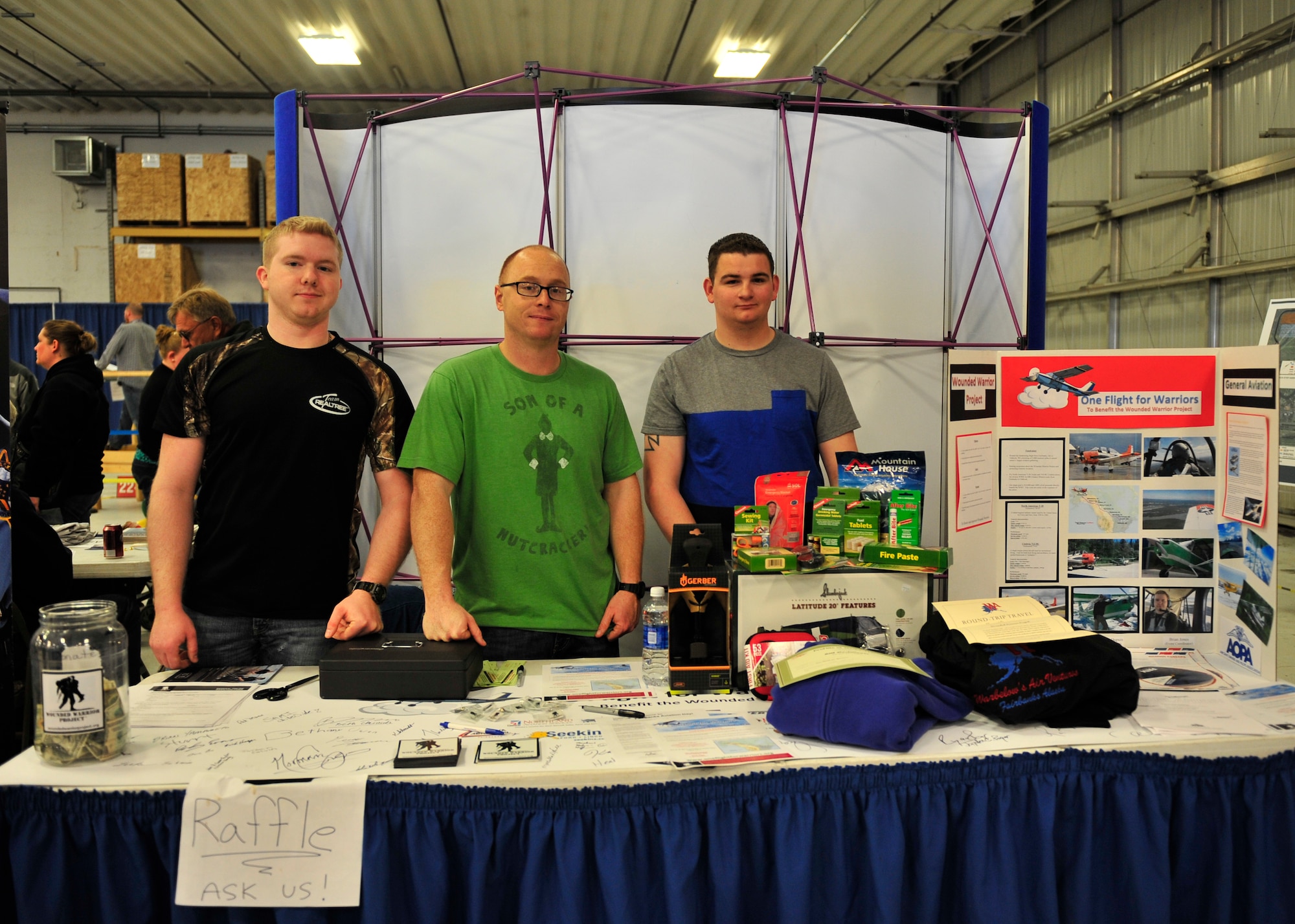 Airman Brian Jones and Airman 1st Class Paul Nadeau, 354th Operations Support Squadron airfield management shift leads, show off their display with Staff Sgt. Phillip Mathews, 354th OSS weather technician, during the Fairbanks Aviation Day May 17, 2014, Fairbanks, Alaska. The three were spreading awareness for the Wounded Warrior Project, and have raised over $5,000 toward the organization so far. (U.S. Air Force photo by Senior Airman Ashley Nicole Taylor/Released)