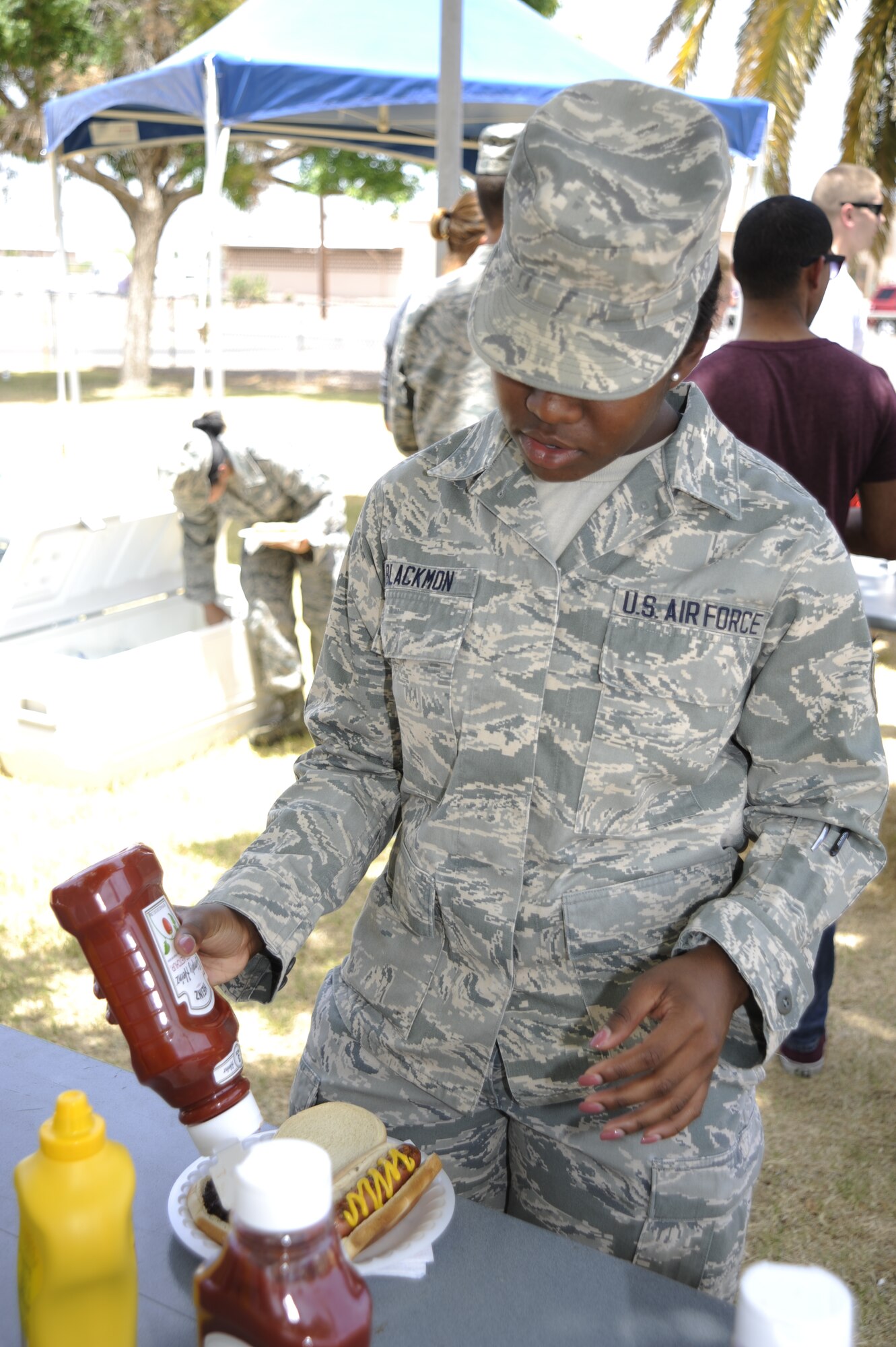 U.S. Air Force Airman 1st Class Sierra Blackmon, 563rd Operations Support Squadron intelligence analyst, applies condiments to her food during the Comprehensive Airman Fitness Day burger burn at Davis-Monthan Air Force Base, Ariz., June 2, 2014. Airmen attended the free lunch in support of social pillar CAF. (U.S. Air Force photo by Airman 1st Class Betty R. Chevalier/Released)