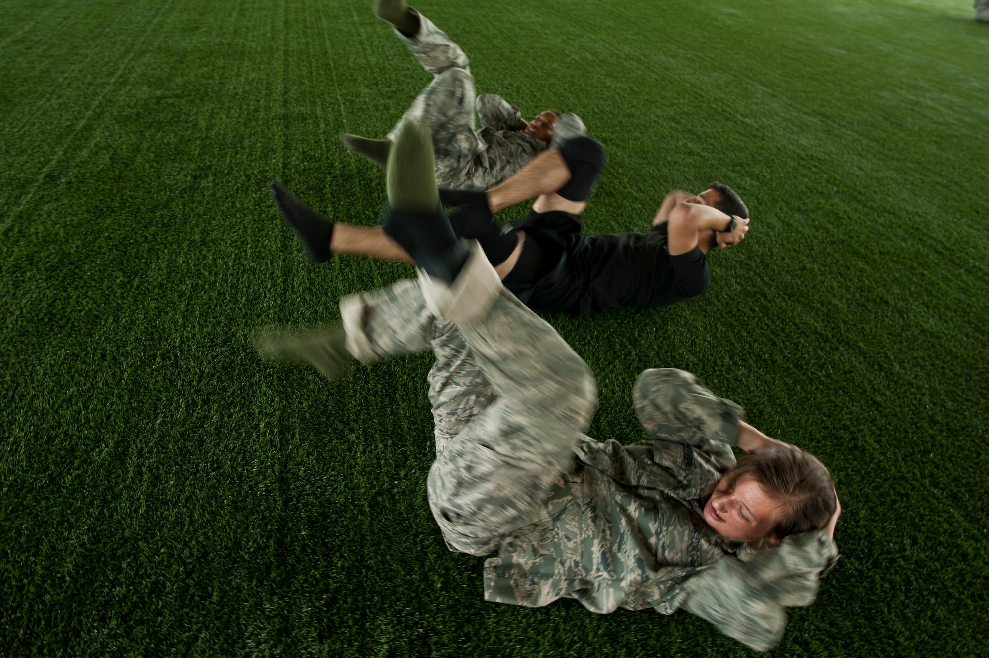 Two Air Force Reserve Officer Training Corps cadets perform bicycle kicks with guidance from an instructor during combatives training on Maxwell Air Force Base, May 29, 2014. The cadets performed a series of calisthenics exercises before sparring to increase their level of fatigue, in an effort to improve stamina and simulate real world hand-to-hand combat conditions. (U.S. Air Force Photo by Staff Sgt. Gregory Brook)