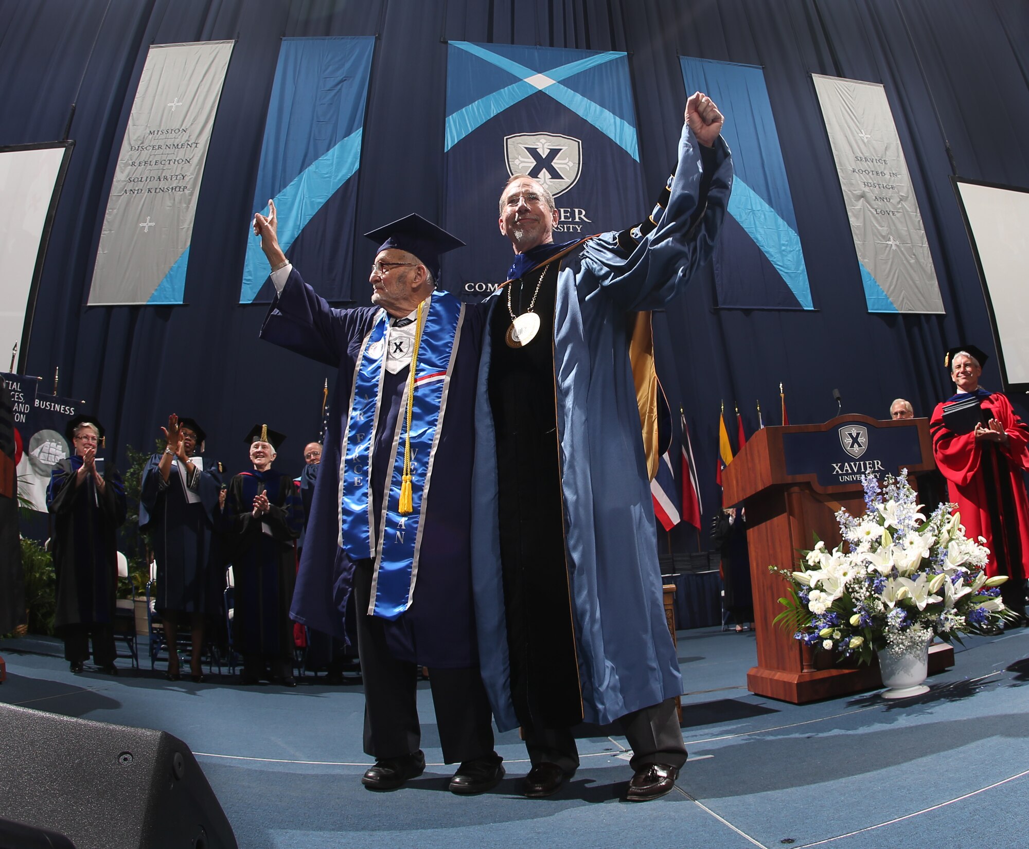 World War II veteran Walter Bunker, left, greets the crowd at Xavier University's 176th commencement along with Xavier University President Michael J. Graham.  Bunker, 90, is believed to be Xavier's oldest undergraduate to receive a degree. (Photo courtesy of Greg Rust, Xavier University)