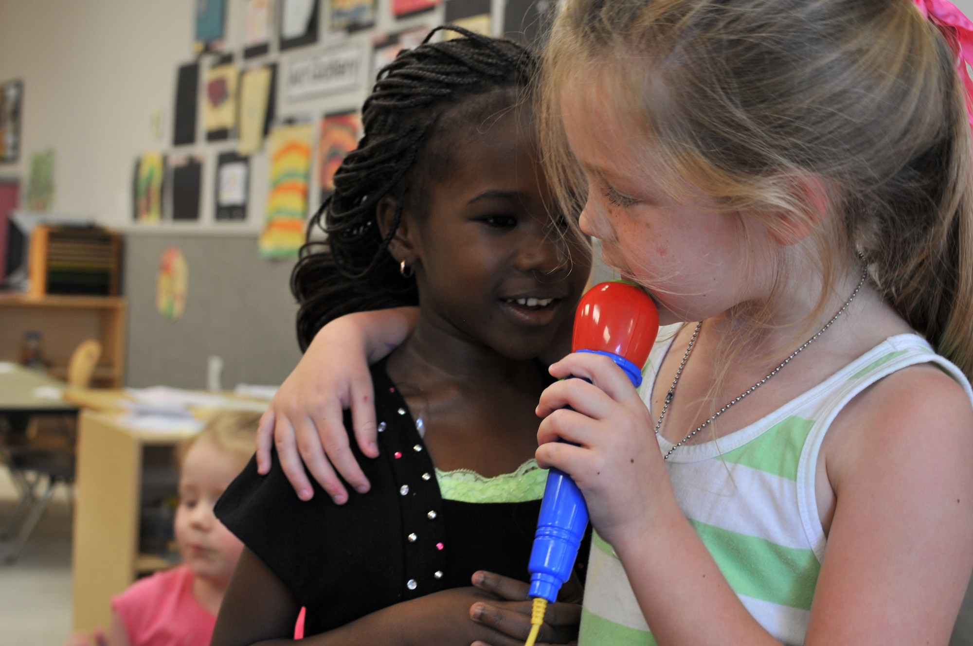 Sarah Caton, a 4-year-old attending the Maxwell Air Force Base child development center, sings to her best friend Fatou Gueye at the CDC, May 20, 2014. Sarah has helped Fatou adjust to American culture since she arrived to the CDC from Senegal in August 2013. (U.S. Air Force photo by Staff Sgt. Natasha Stannard)