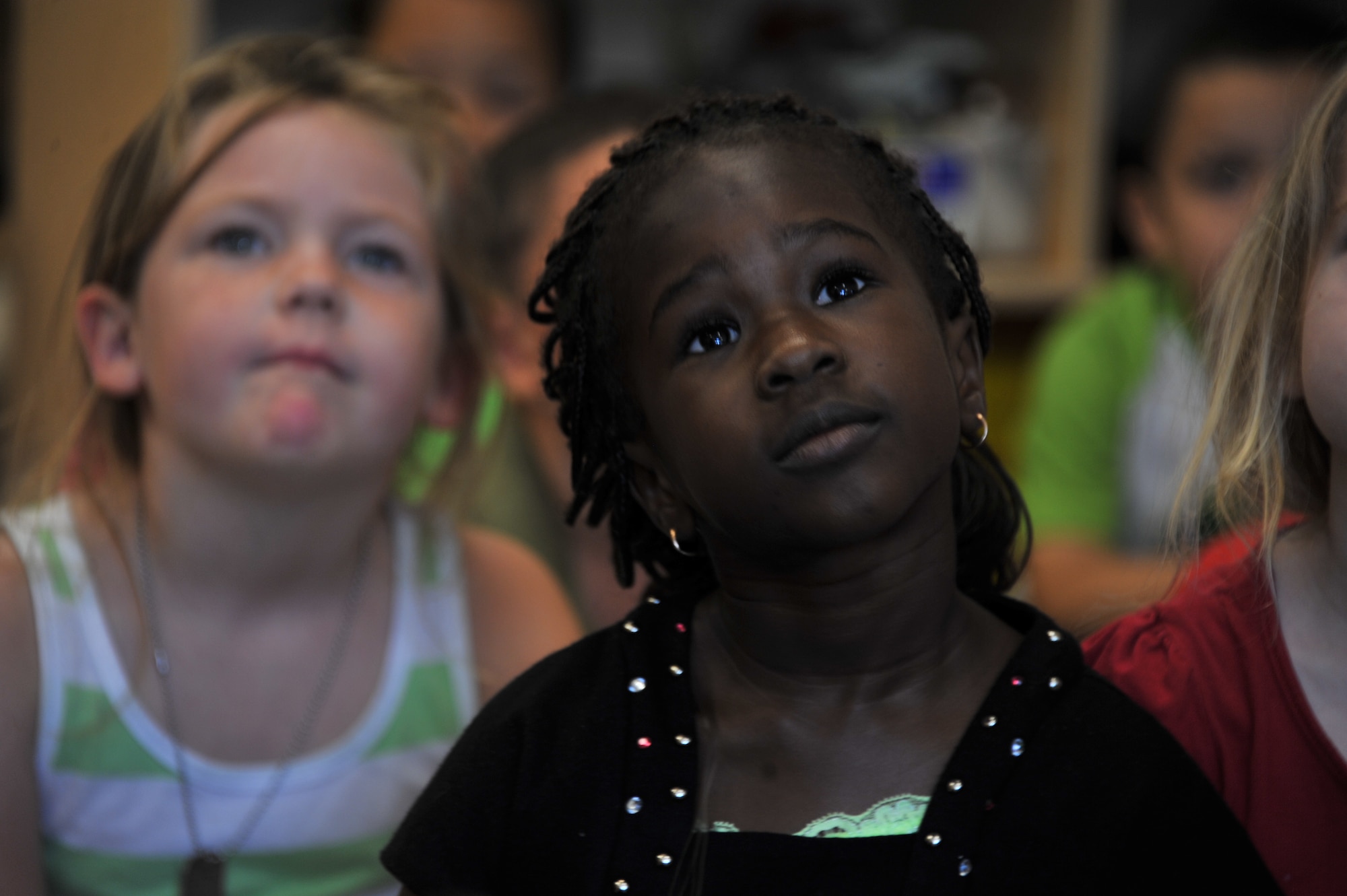 Fatou Gueye, right, and Sarah Caton, both 4-year-olds attending the Maxwell Air Force Base child development center, listen to their teacher read a book, May 20, 2014. When Fatou, who is from Senegal, first arrived to the CDC in August 2013, she did not speak any English. Sarah and some of the other children helped Fatou learn the new language, and made her feel welcome. (U.S. Air Force photo by Staff Sgt. Natasha Stannard)