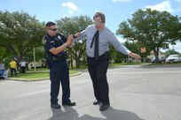 Officer Rueben Morales, Universal City Police Department  helps Mark Tharp walk a straight line, while wearing  fatal vision goggles June 4, 2014 during the Critical Days of Summer event at Joint Base San Antonio-Randolph.  These goggles gives the individual  a view on how things are seen after alcohol consumption.  (U.S. Air Force photo by Joel Martinez)