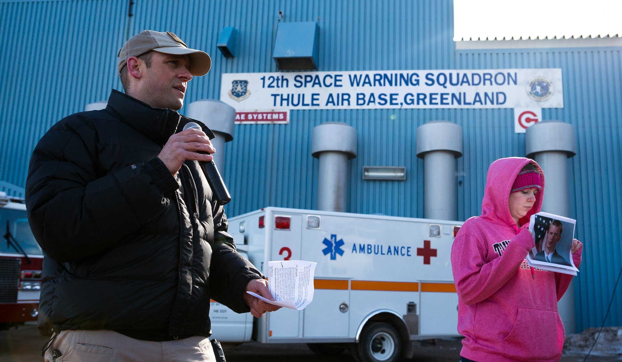THULE AIR BASE, Greenland – Lt. Col. Jim Lovewell, 821st Air Base Group deputy commander and honorary race marshal, delivers a speech to runners and volunteers prior to the Memorial Day Array-to-the-Bay Relay Run as Staff Sgt. Joanne Sherred, 821st Support Squadron, holds a picture of Capt. David Lyon. Lyon and Airman 1st Class Matthew Seidler, both members of the 21st Space Wing, were killed in action in Afghanistan and were honored at the event. (Courtesy photo/Torben Bjerre)