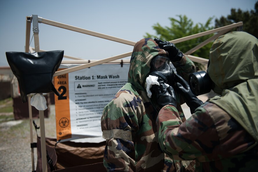 Staff Sgt. Jon Andrew, 8th Medical Operations Squadron bioenvironmental technician, and a Republic of Korea Airman decontaminate their protective masks while processing through a contamination control area during a combined exercise at Kunsan Air Base, Republic of Korea, May 28, 2014. This exercise tested the response of the Wolf Pack and RoKaf to a chemical threat. (U.S. Air Force photo by Staff Sgt. Clayton Lenhardt/Released)