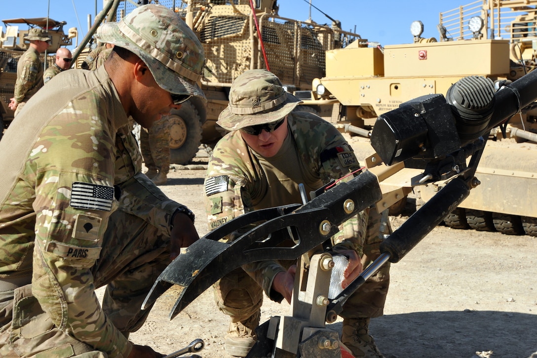 U.S. Army Spc. Tomas Paris, left, and U.S. Army Sgt. Jeffrey Maloney set up the mechanical claw on Maloney's vehicle before a night route clearance mission on Forward Operating Base Shank in Afghanistan's Logar province, May 23, 2014. Paris, a mechanic, and Maloney, a heavy equipment operator, are assigned to the 10th Mountain Division's Company A, 3rd Brigade Special Troops Battalion, 3rd Brigade Combat Team, Combined Arms Route Clearance Operation 30.