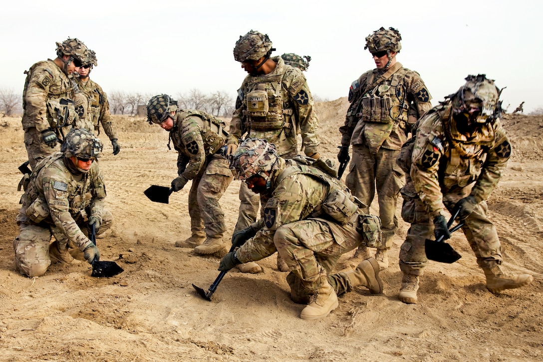 U.S. soldiers use entrenching tools to level the ground during construction in the Zharay district in Afghanistan's Kandahar province, Feb. 10, 2012. The soldiers are assigned to the 10th Mountain Division's Company A, Brigade Special Troops Battalion, 3rd Brigade Combat Team.  
