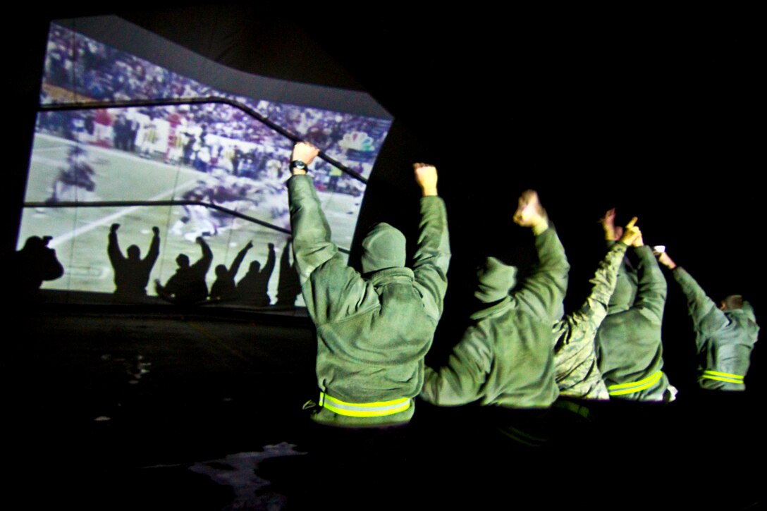 U.S. Air Force airmen watch the Super Bowl projected onto the interior of an aircraft hangar on Bagram Airfield, Afghanistan, Feb. 6, 2012. The airmen are assigned to the 455th Expeditionary Aircraft Maintenance Squadron. The game aired live in the early hours of Feb. 6.  
