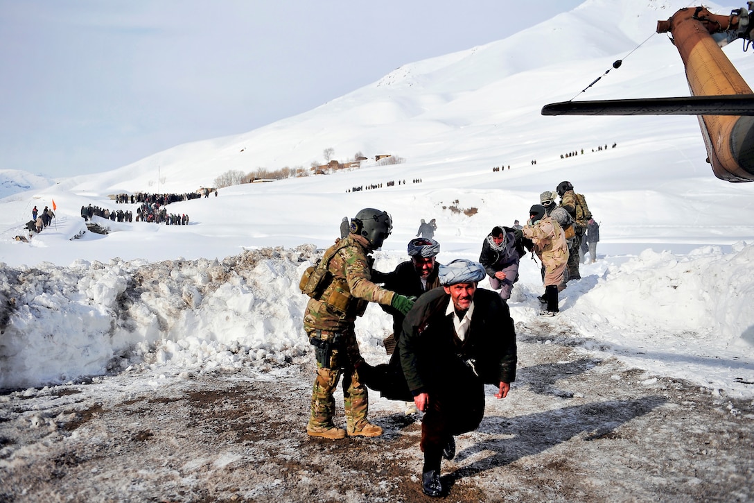 U.S. Air Force Staff Sgt. Jonathan Hill, left, directs villagers to his Mi-17 helicopter in Shewa village in Afghanistan's Badakhshan province, Jan. 24, 2012. Hill is an Mi-17 helicopter engineer assigned to the 438th Air Expeditionary Advisory Squadron.  
