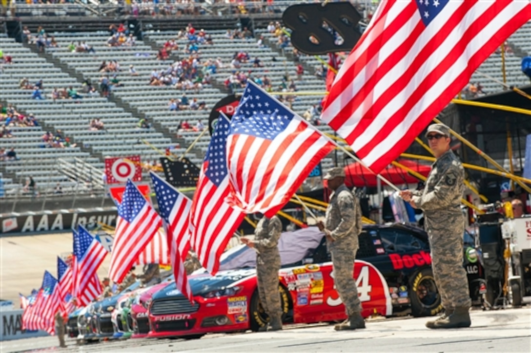 Military service members hold U.S. flags as a sign of patriotism before the start of the FedEx 400 NASCAR race at the Dover International Speedway in Dover, Del., June 1, 2014. 