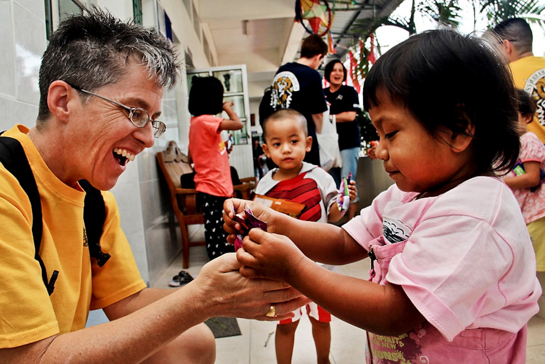 U.S. Navy Master Chief Petty Officer Susan Whitman shares candy with a young girl during a community service project at the Camillian Social Center for children and adults living with HIV and AIDS in Rayong, Thailand, Jan. 7, 2012. Whitman is command master chief petty officer of the USS Abraham Lincoln.  
