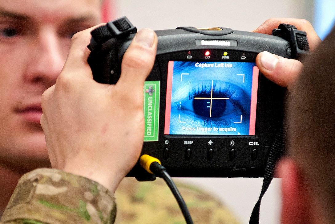 A paratrooper scans the iris of a soldier using a Handheld Interagency Identity Detection Equipment, or HIIDE, system during training at the Joint Readiness Training Center on Fort Polk, La., Jan. 10, 2012.  
