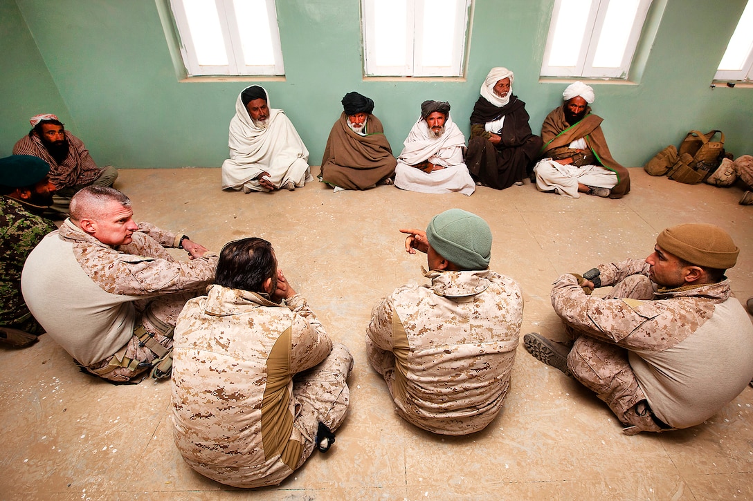 An interpreter, center, explains the concerns of Afghan elders to U.S. Marine Corps Col. Roger Turner, left, and Lt. Col. Matthew Palma, far right, in a shura at a school during Operation Tageer Shamal in Afghanistan's Helmand province, Jan. 6, 2012. Turner is the commanding officer of the 5th Marine Regiment and Palma is the commanding officer of the 3rd Battalion, 3rd Marine Regiment. 
